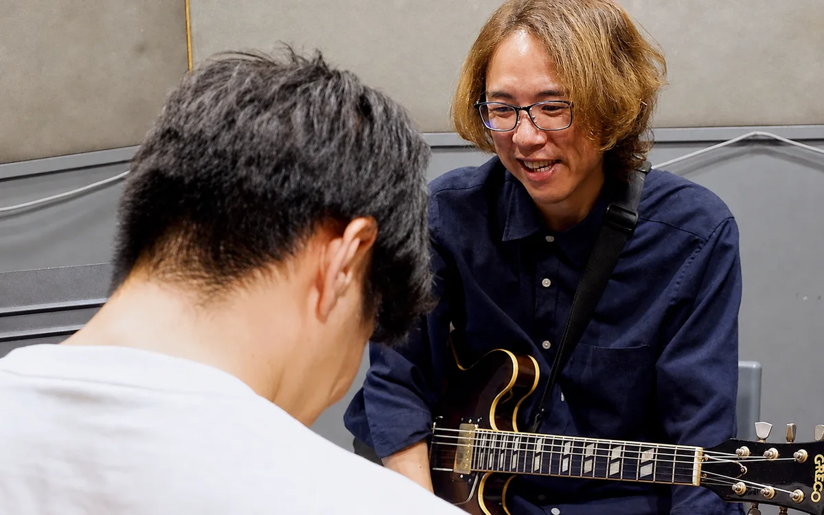 先生が生徒さんと一緒に手元を見ながら教える様子