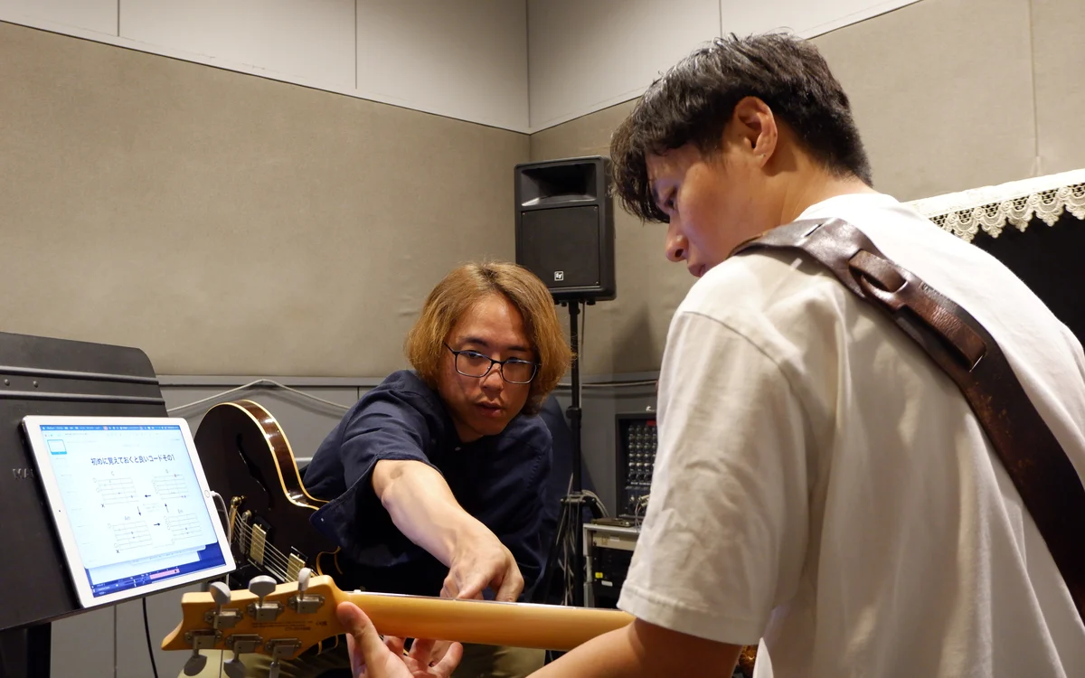 先生が手を伸ばして、生徒さんに指の位置を教える様子